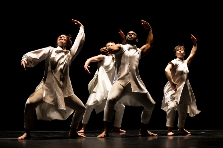 Dancers performing on stage, with arms raised overhead